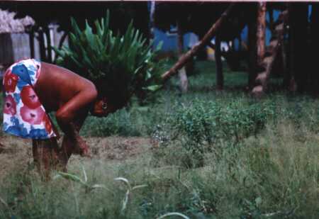 Lady cutting the grass with a machette